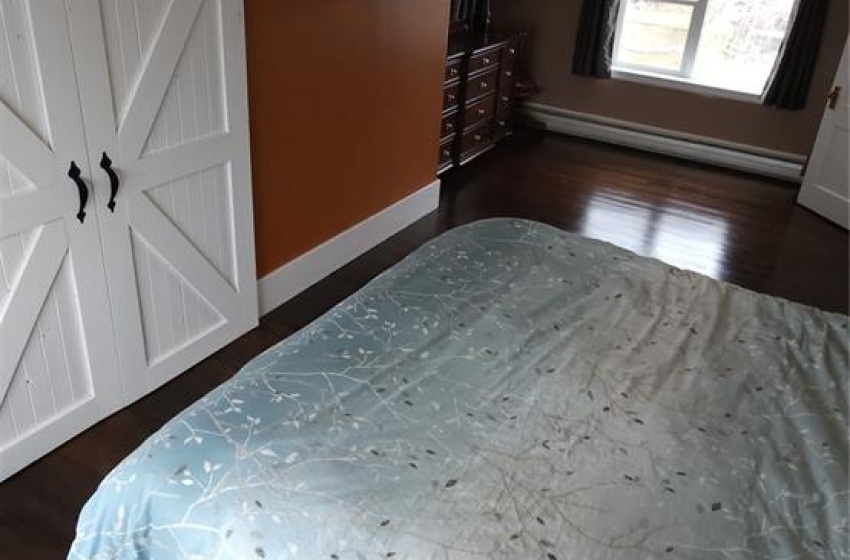 Unfurnished bedroom with dark wood-type flooring and a barn door