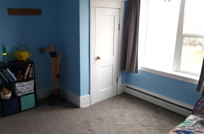 Bedroom featuring dark colored carpet, a baseboard radiator, and ceiling fan