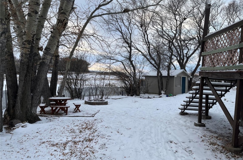 Snowy yard featuring a storage shed and pond area