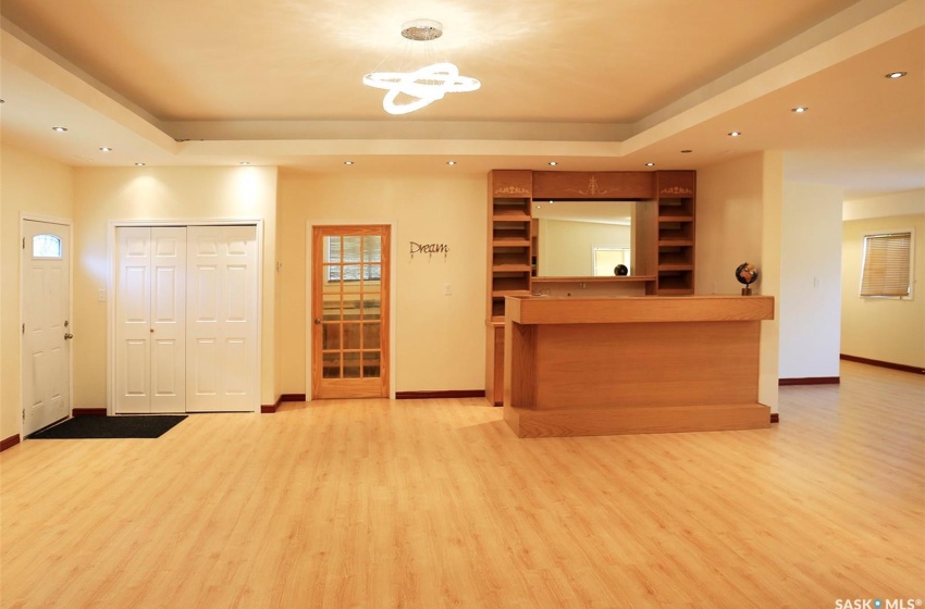 Kitchen with light wood-type flooring, a raised ceiling, an inviting chandelier, and pendant lighting