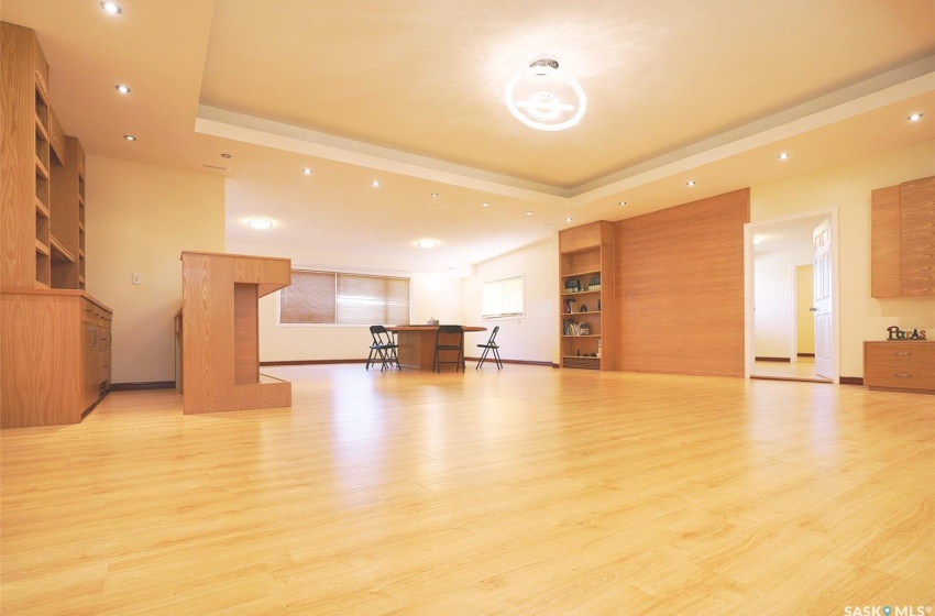 Unfurnished living room with a raised ceiling, built in shelves, and light hardwood / wood-style flooring