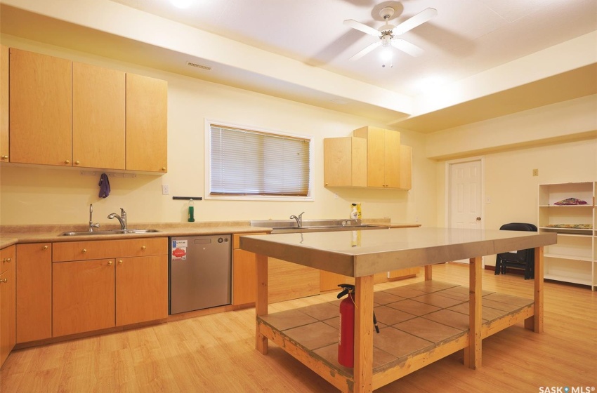 Kitchen featuring light brown cabinets, sink, light hardwood / wood-style floors, stainless steel dishwasher, and ceiling fan