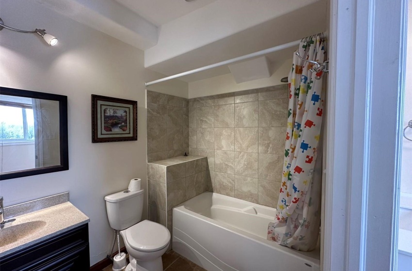 Full bathroom featuring tile floors, toilet, vanity, and shower / bath combo with shower curtain