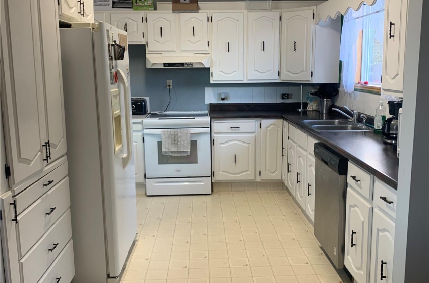 Kitchen featuring light tile flooring, sink, white appliances, and white cabinetry