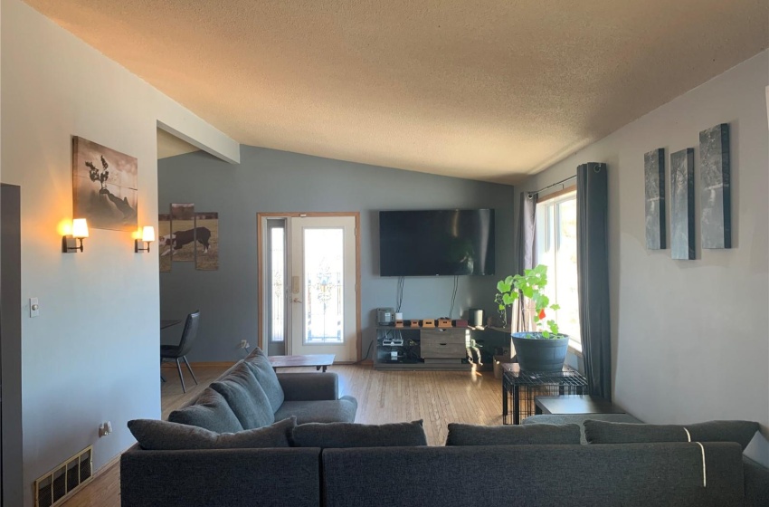 Living room featuring a textured ceiling, vaulted ceiling, and light hardwood / wood-style flooring