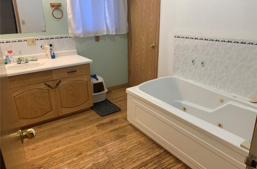 Bathroom with backsplash, vanity, a washtub, and hardwood / wood-style flooring