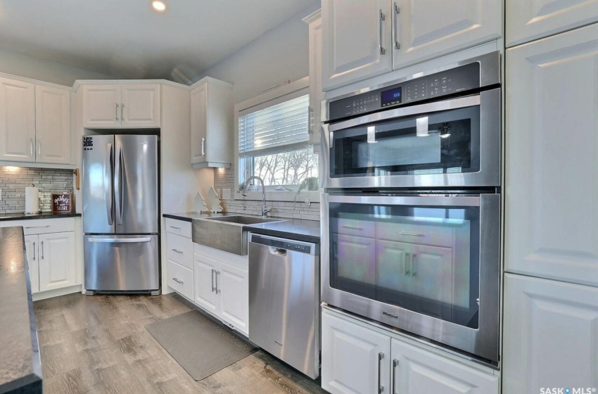 Kitchen featuring sink, appliances with stainless steel finishes, light hardwood / wood-style floors, tasteful backsplash, and white cabinetry