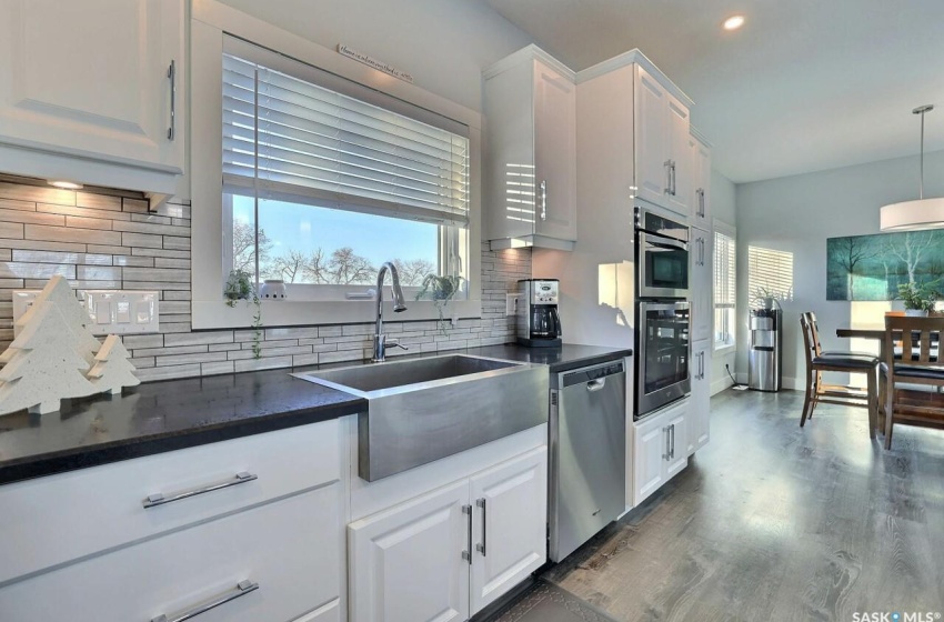 Kitchen featuring appliances with stainless steel finishes, pendant lighting, dark hardwood / wood-style floors, tasteful backsplash, and white cabinetry