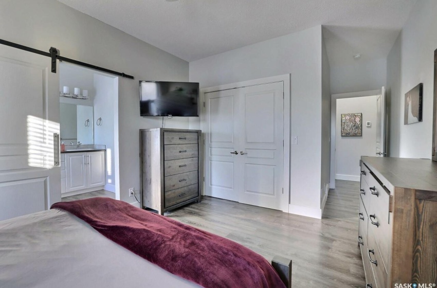 Bedroom with ensuite bathroom, a closet, light hardwood / wood-style floors, and a barn door