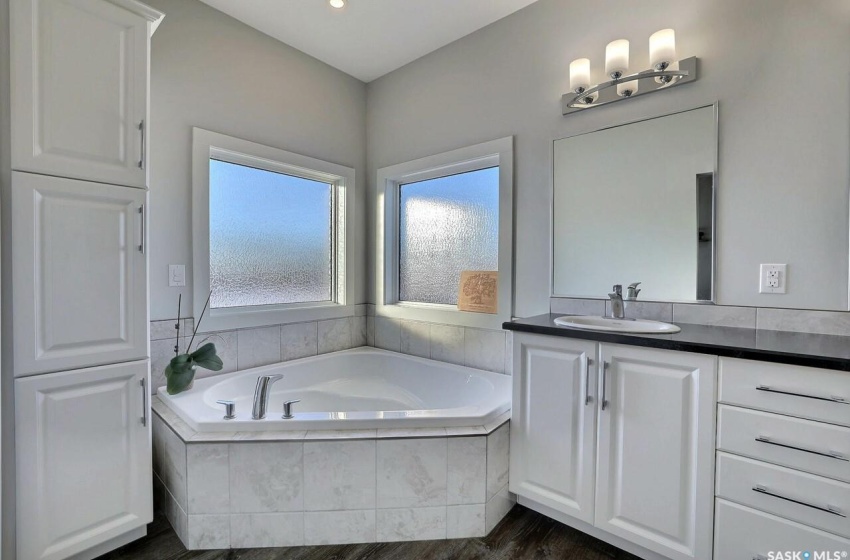 Bathroom with vanity, wood-type flooring, and tiled tub