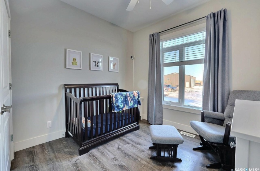 Bedroom featuring ceiling fan, a crib, and hardwood / wood-style flooring