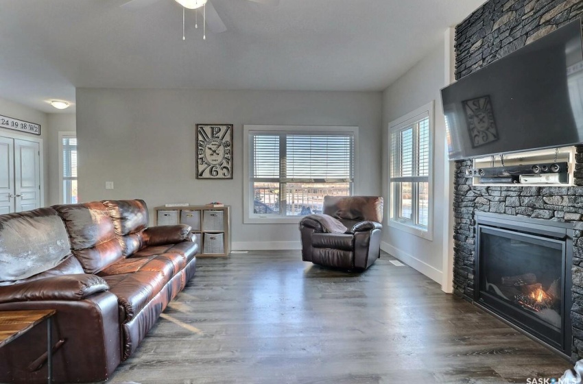 Living room featuring ceiling fan, hardwood / wood-style floors, and a stone fireplace