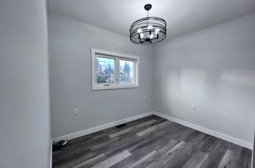 room with dark hardwood / wood-style flooring and a chandelier