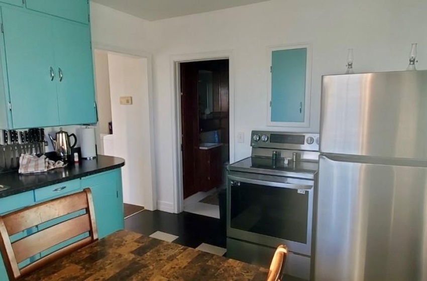 Kitchen featuring dark hardwood / wood-style flooring, sink, stainless steel fridge, blue cabinets, and range with electric stovetop