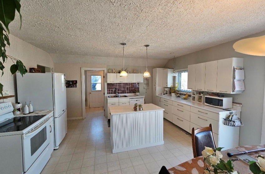 Kitchen featuring light tile floors, white appliances, plenty of natural light, and white cabinetry