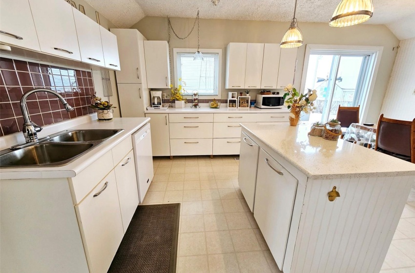 Kitchen with white appliances, a kitchen island, white cabinetry, and vaulted ceiling