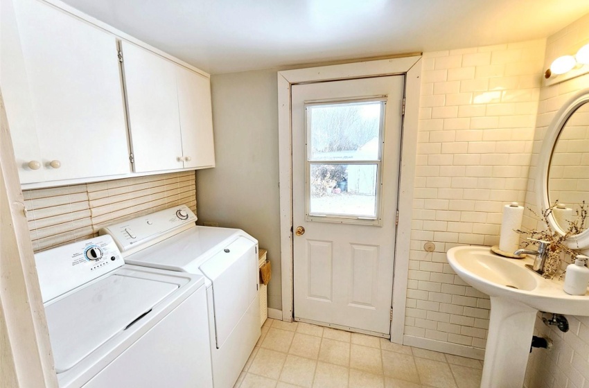 Laundry area with washer and dryer, tile walls, and light tile floors