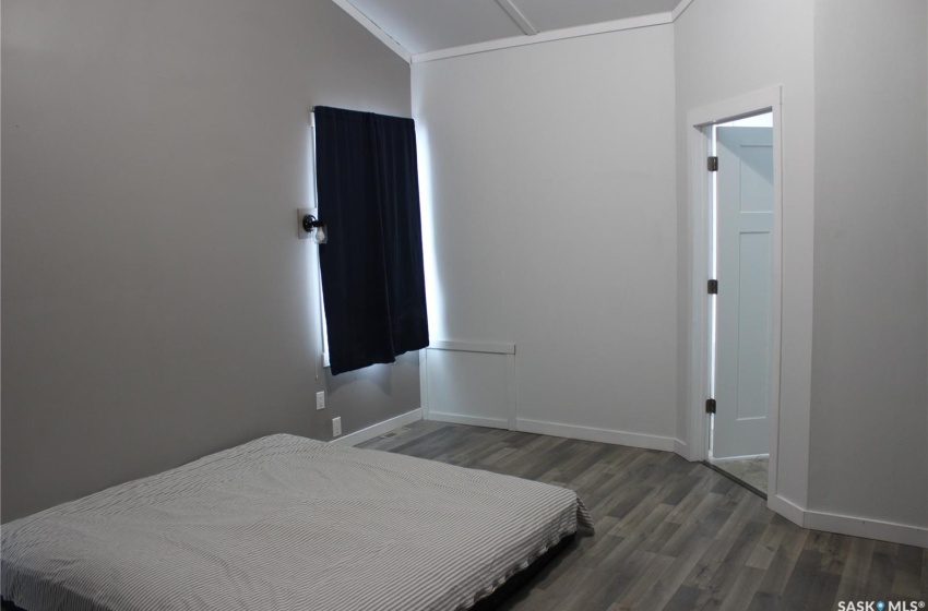 Bedroom with ornamental molding, lofted ceiling, and dark wood-type flooring