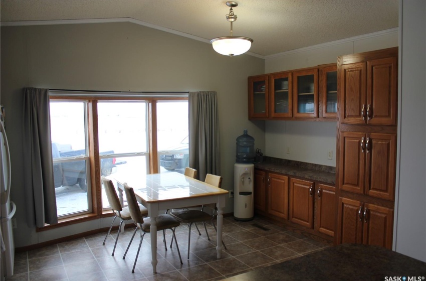 Dining room featuring a healthy amount of sunlight, lofted ceiling, dark tile floors, and crown molding