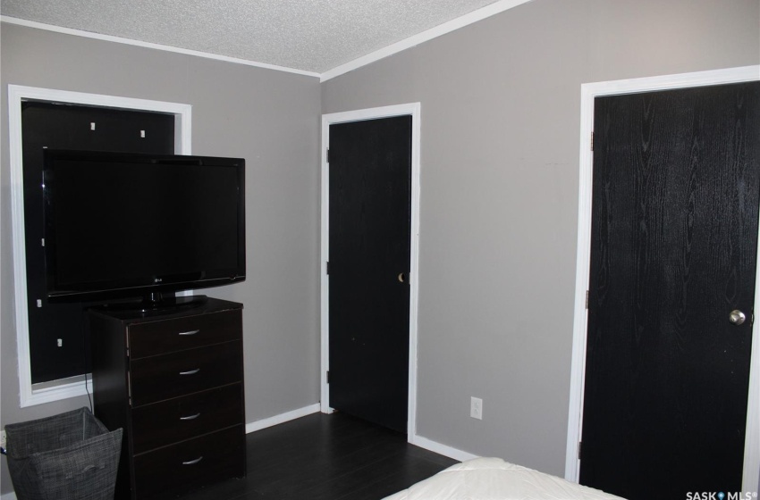 Bedroom featuring dark hardwood / wood-style flooring, vaulted ceiling, a textured ceiling, and ornamental molding