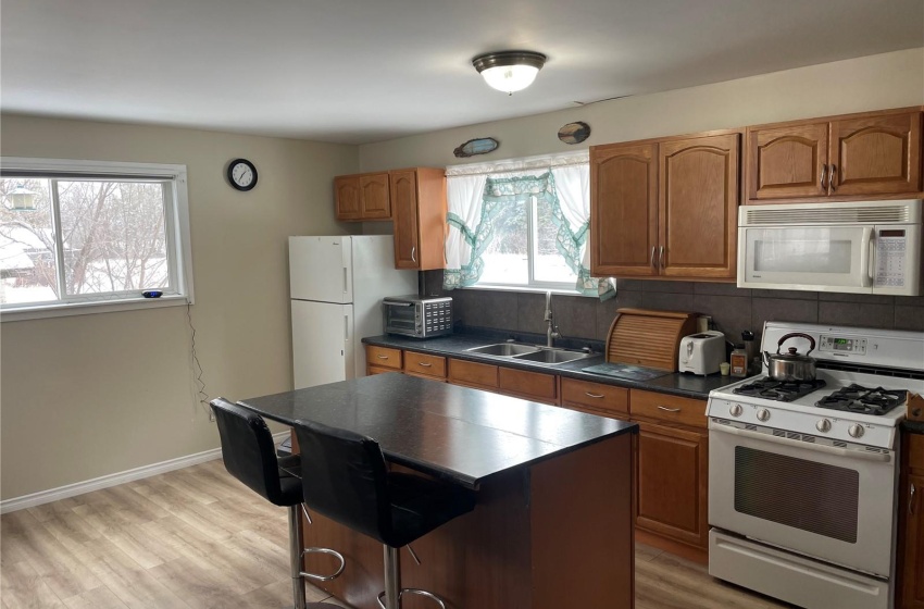 Kitchen a breakfast bar area, a center island, sink, and white appliances