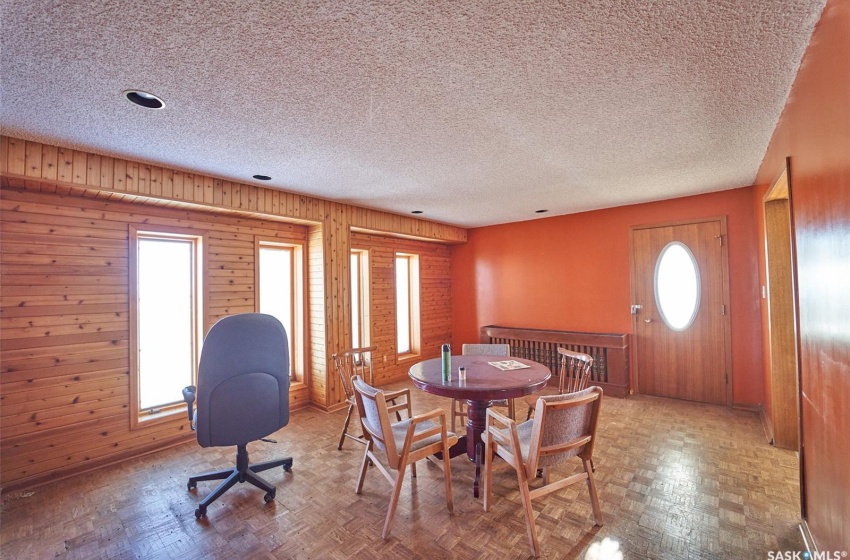 Dining space featuring wood walls, parquet flooring, and a textured ceiling