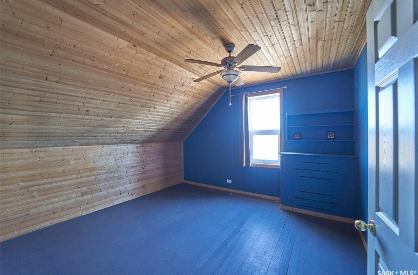 Additional living space featuring wood walls, wood ceiling, dark wood-type flooring, ceiling fan, and lofted ceiling