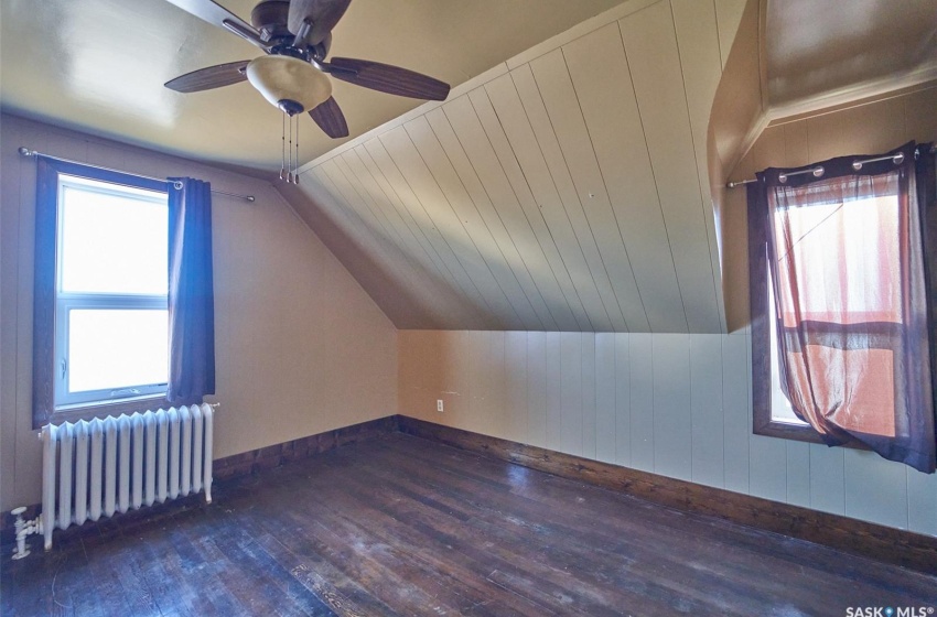 Additional living space featuring ceiling fan, a wealth of natural light, dark hardwood / wood-style flooring, and radiator heating unit