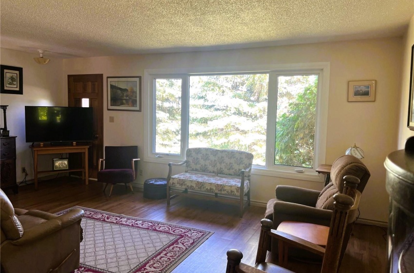 Living room with dark wood-type flooring, a textured ceiling, and plenty of natural light