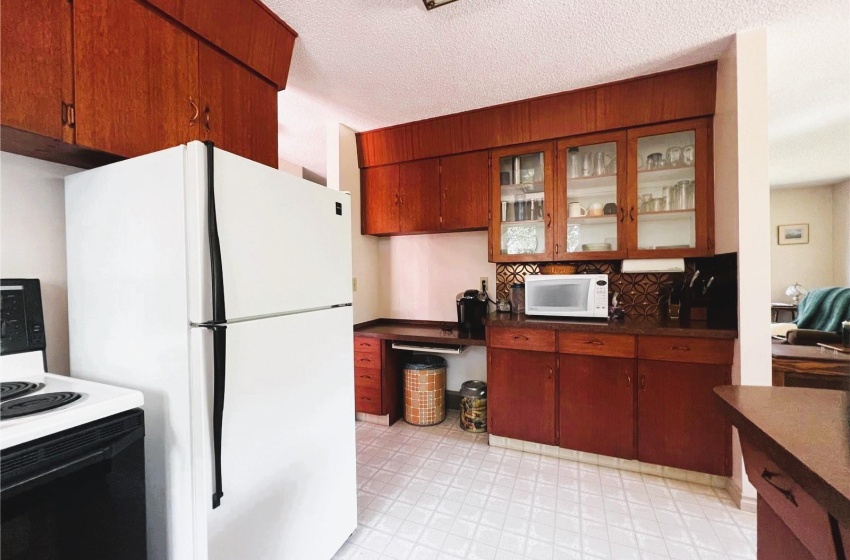 Kitchen featuring, white appliances, a textured ceiling,