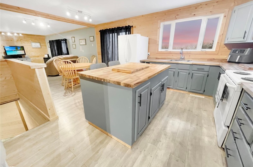 Kitchen featuring white appliances, a center island, rail lighting, butcher block countertops and a view of the yard