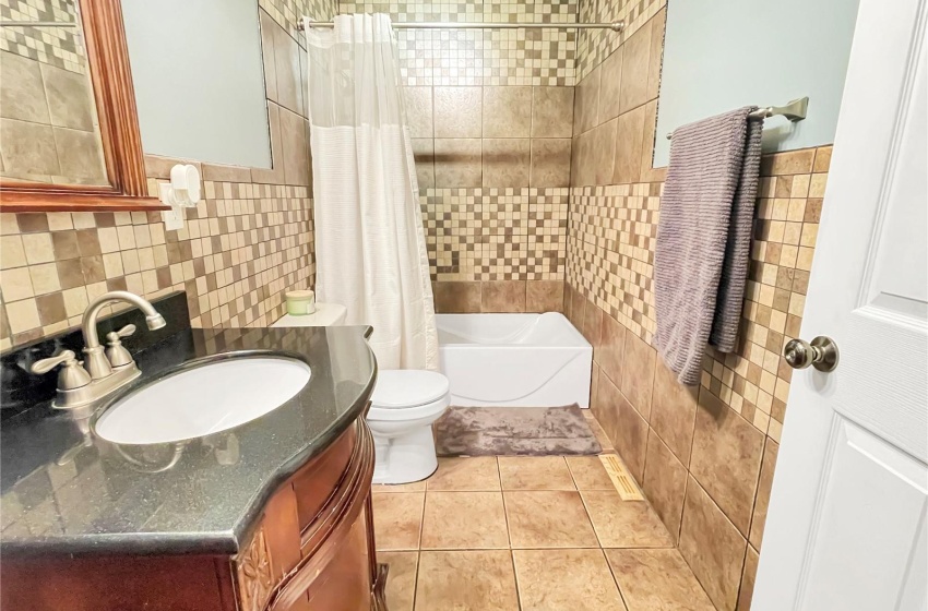 Full main bathroom featuring tile floors, vanity with extensive cabinet space, tile walls, and tiled shower / bath combo