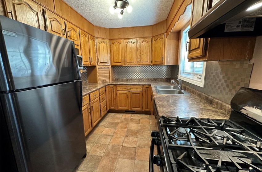 Kitchen with premium range hood, sink, tasteful backsplash, and black appliances