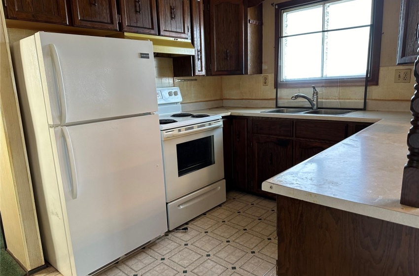 Kitchen featuring white appliances, light tile floors, sink, tasteful backsplash, and dark brown cabinets