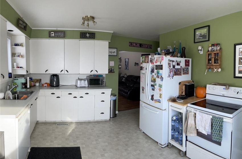 Kitchen featuring sink, light tile flooring, white appliances, and white cabinetry