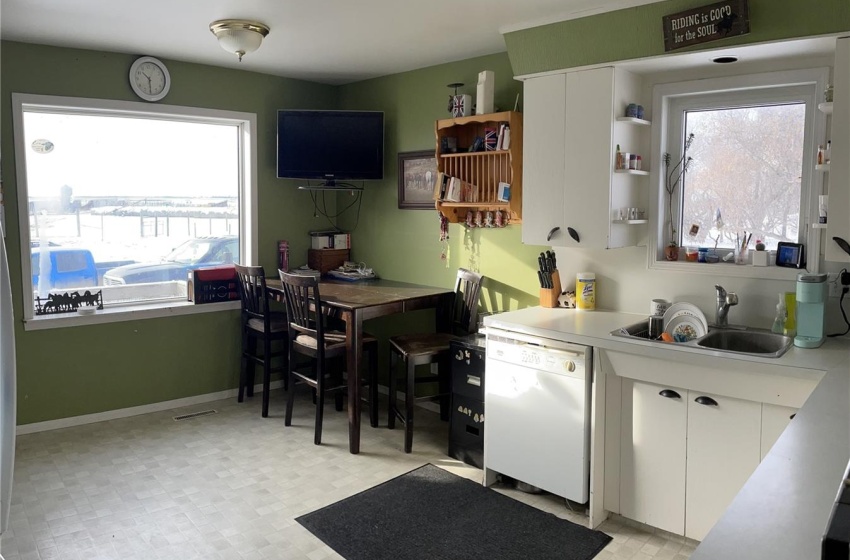 Kitchen with plenty of natural light, white cabinets, light tile flooring, and white dishwasher