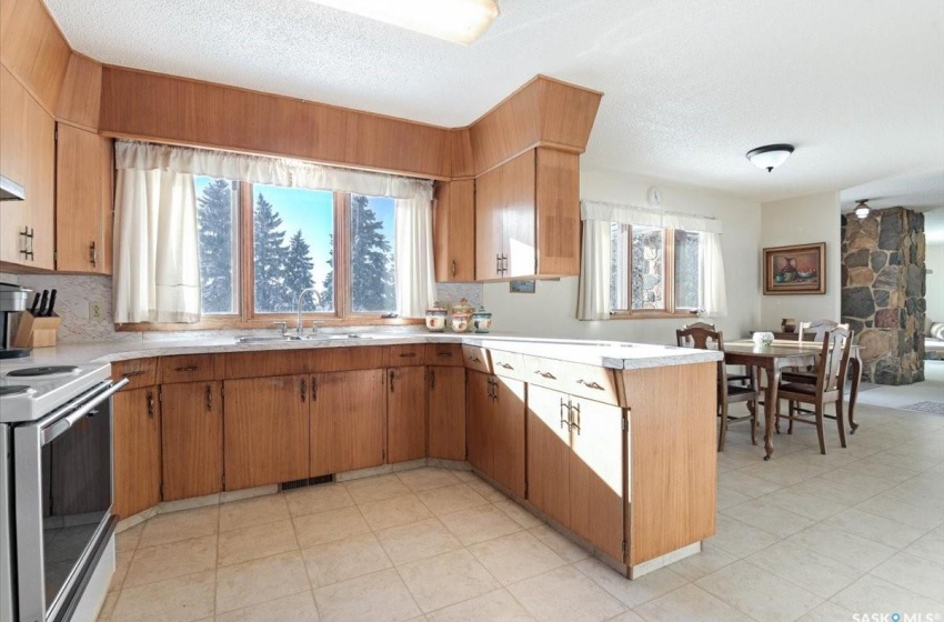 Kitchen featuring electric range, sink, a textured ceiling, and light tile floors