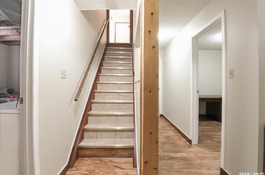 Stairway with washer / dryer, light wood-type flooring, and a textured ceiling