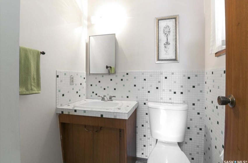 Bathroom with tasteful backsplash, toilet, vanity with extensive cabinet space, and tile walls