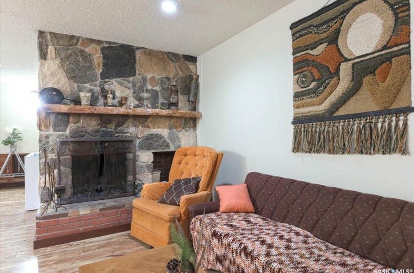 Living room featuring a stone fireplace, a textured ceiling, and light hardwood / wood-style floors