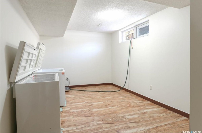 Clothes washing area with light wood-type flooring and a textured ceiling