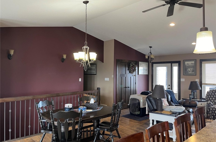 Dining room with dark hardwood / wood-style floors, ceiling fan with notable chandelier, and lofted ceiling