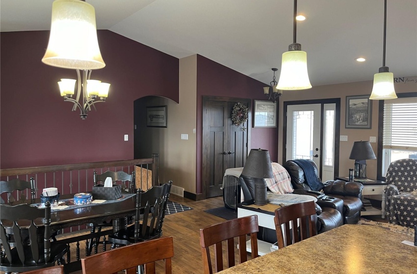 Dining space with ceiling fan with notable chandelier, lofted ceiling, and dark hardwood / wood-style flooring