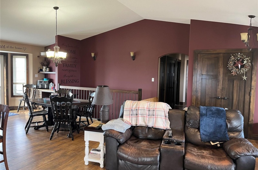 Living room featuring ceiling fan with notable chandelier, hardwood / wood-style flooring, and vaulted ceiling