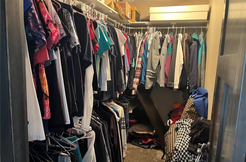 Spacious master bedroom closet featuring dark colored carpet