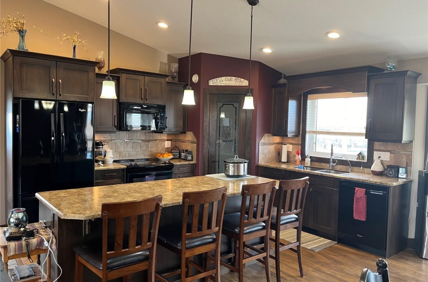 Kitchen featuring a kitchen island, backsplash, black appliances, vaulted ceiling, and sink