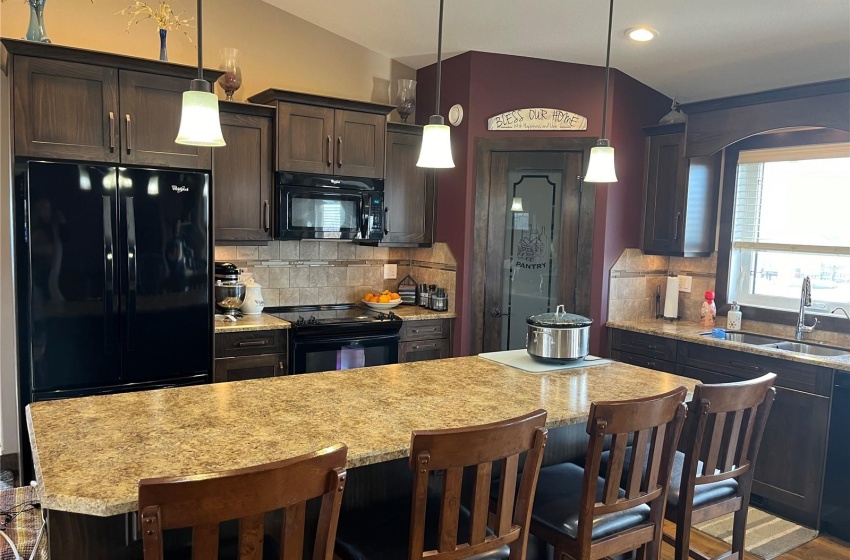 Kitchen featuring lofted ceiling, tasteful backsplash, sink, dark hardwood / wood-style floors, and black appliances