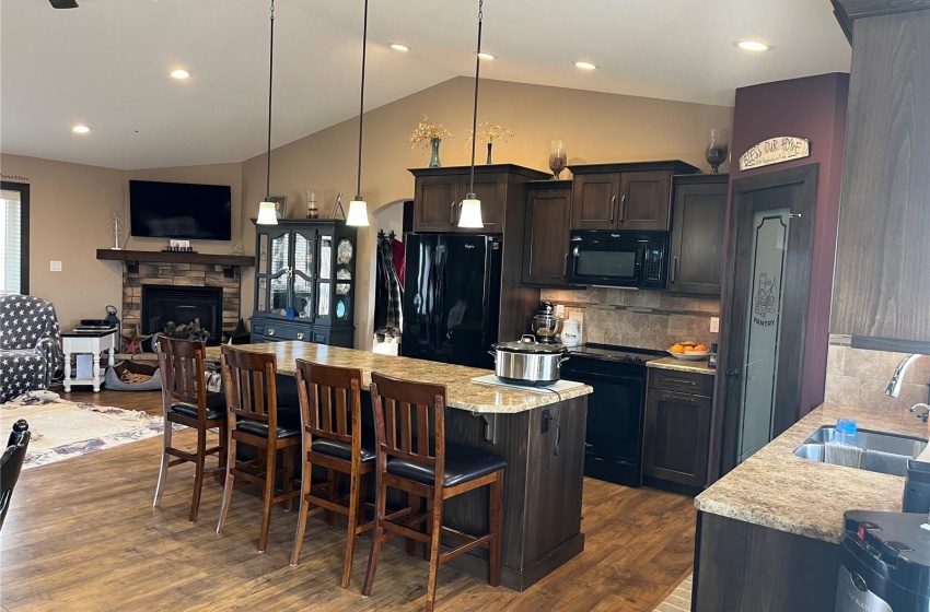 Kitchen with dark hardwood / wood-style flooring, sink, vaulted ceiling, black appliances, and ceiling fan