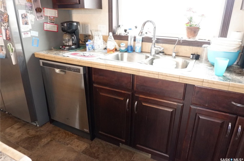 Kitchen featuring dark brown cabinets, tile counters, dark tile floors, sink, and dishwasher