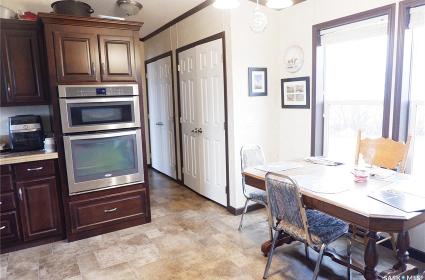 Kitchen with pendant lighting, double oven, ornamental molding, dark brown cabinetry, and light tile floors